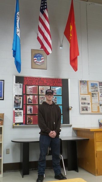 Justin in Fire-Rescue-EMR standing in front of three flags.