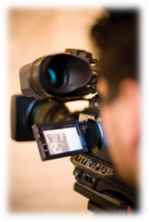Picture of a young man looking through a digital movie camera