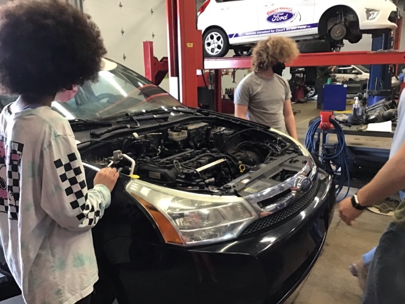 Students working on changing engine